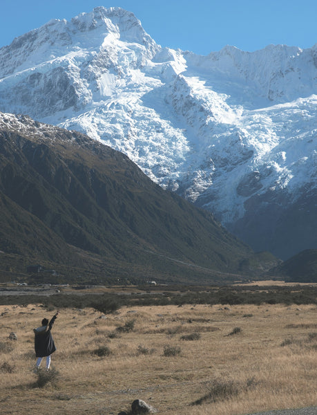 person in black jacket standing at the bottom of the mountain