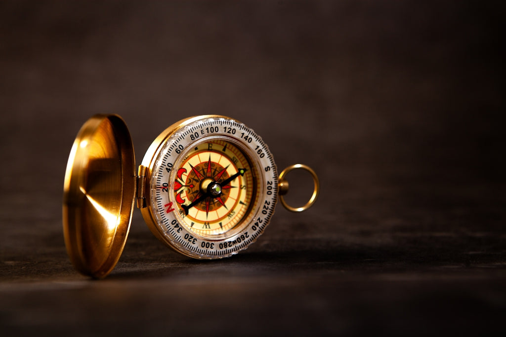 A vintage brass compass rests on a dark surface.